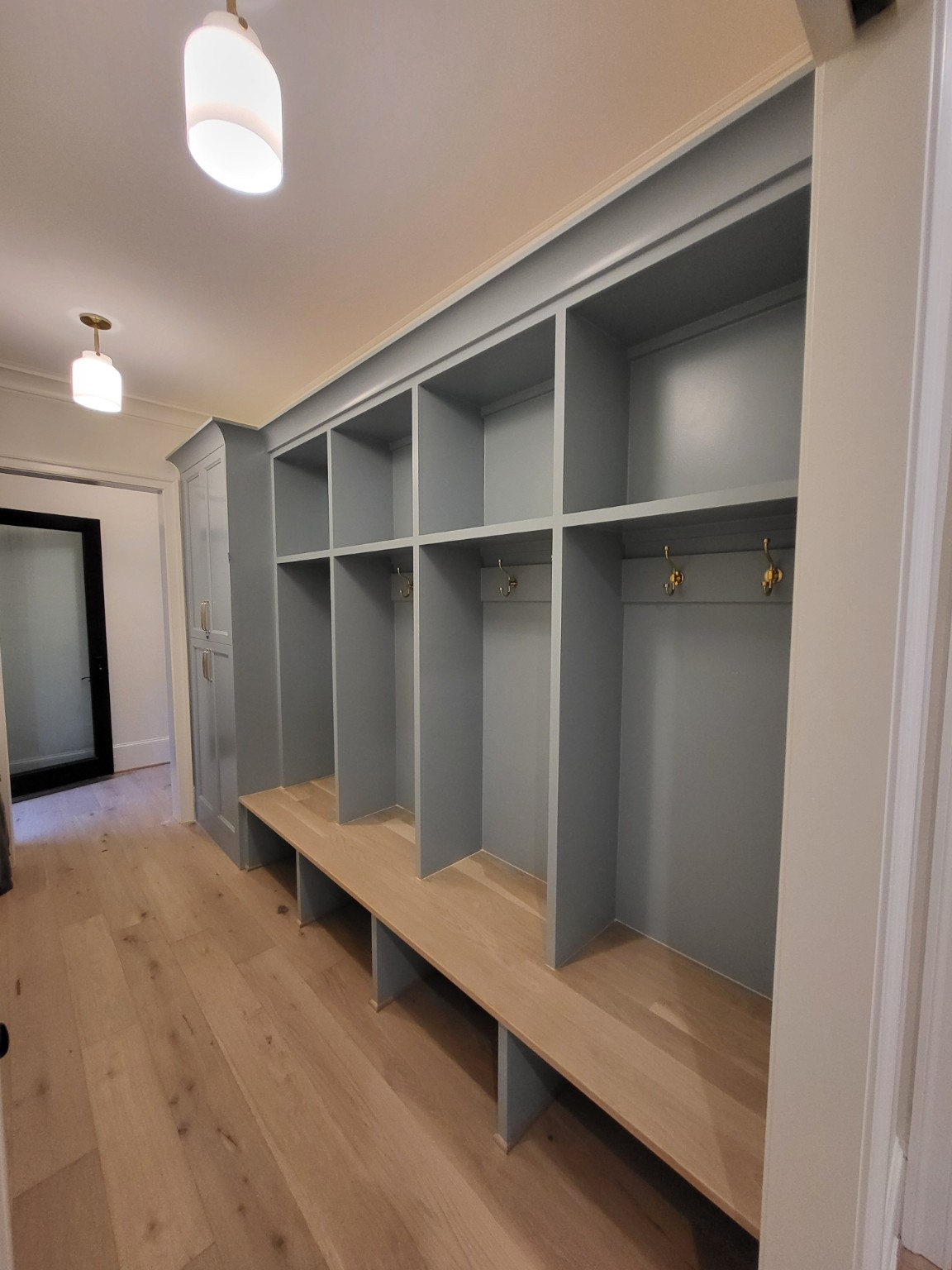 Mudroom with custom gray lockers and wood bench