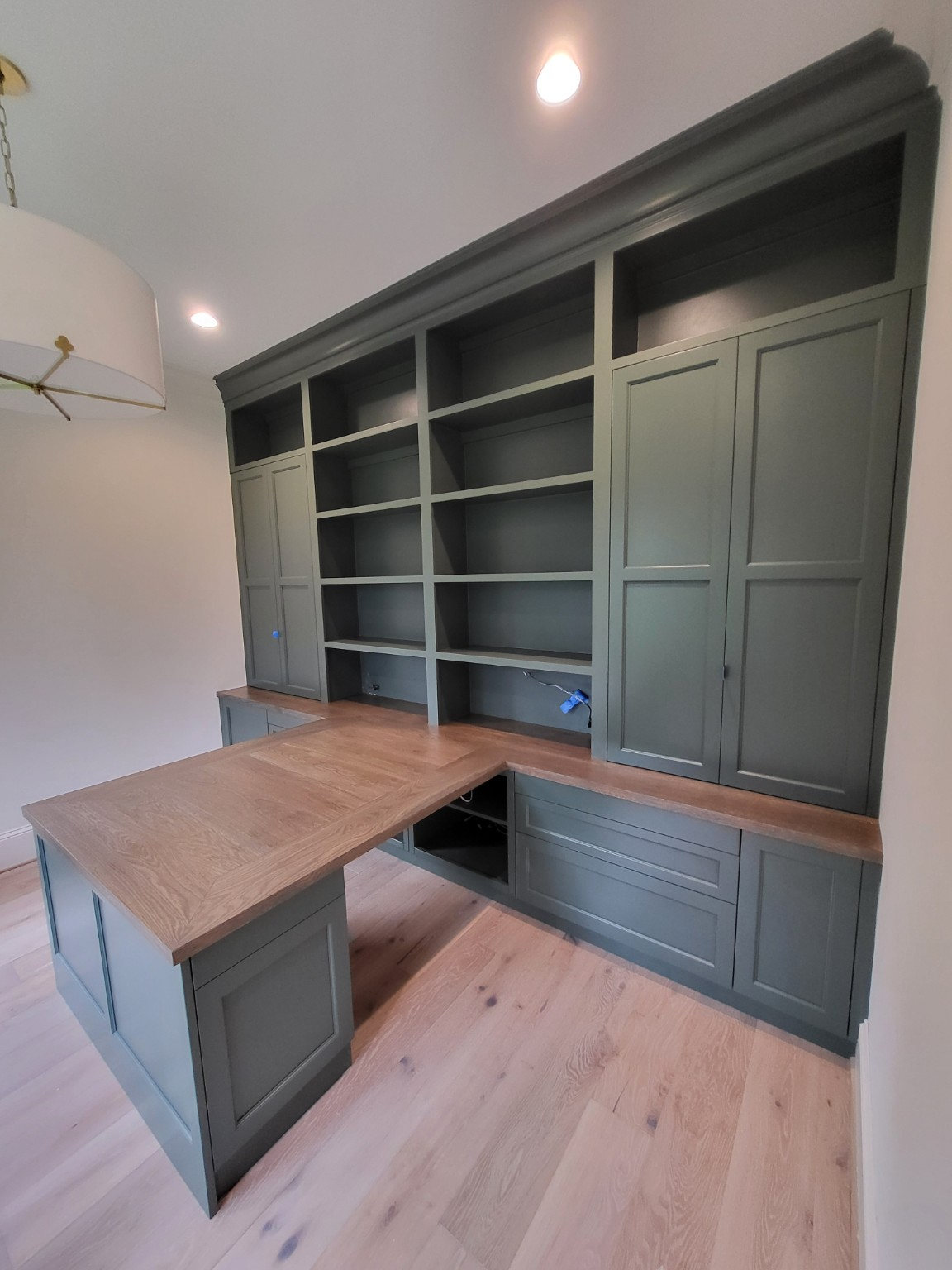 Custom green home office built-ins with wood desktop