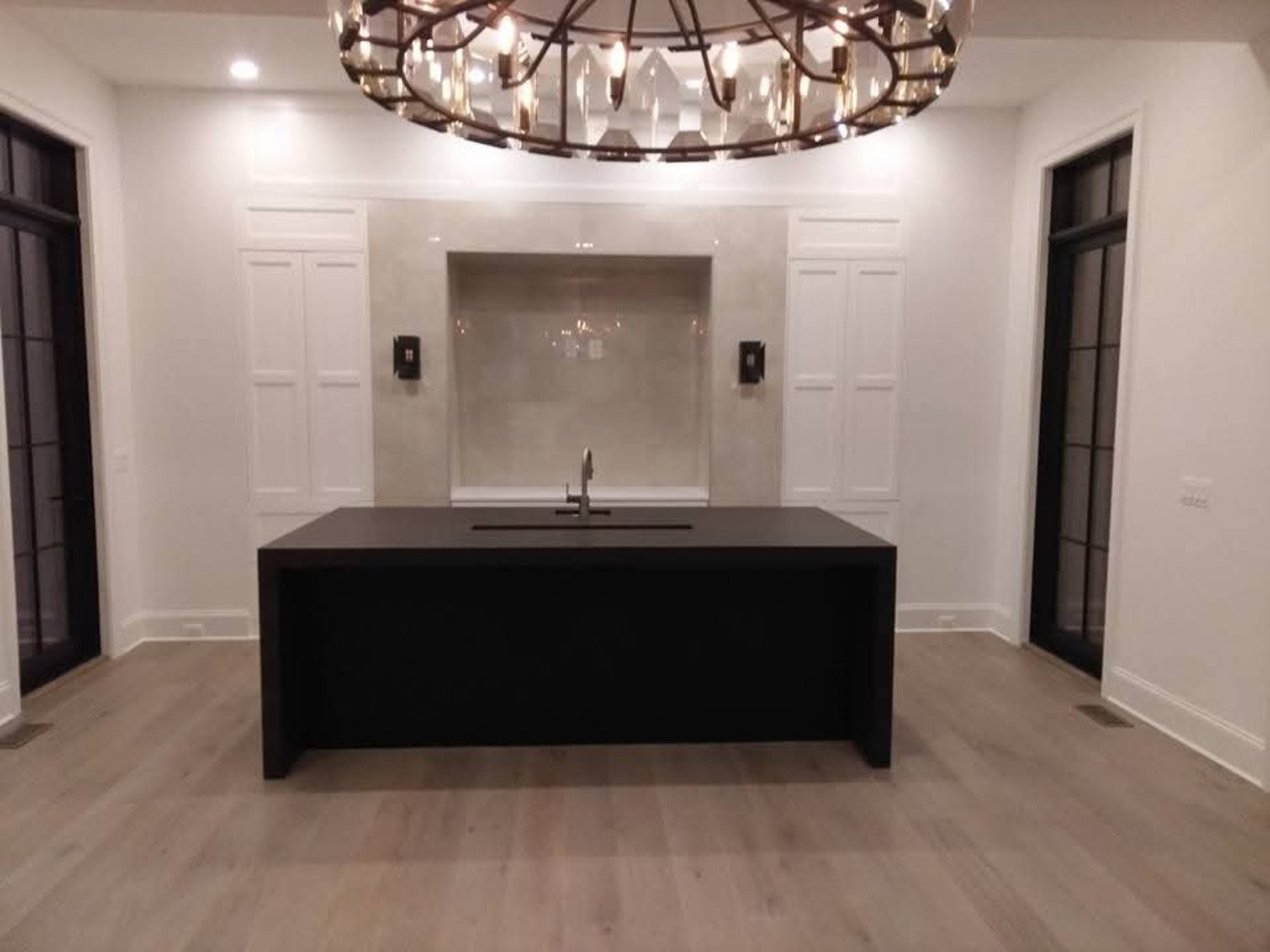 Custom wet bar with waterfall countertop and concealed refrigerators and wine coolers behind integrated wall panels